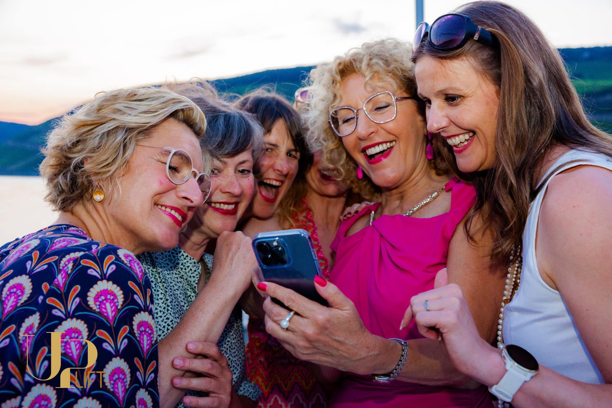 Frauen lachen gemeinsam über ein Foto auf dem Handy