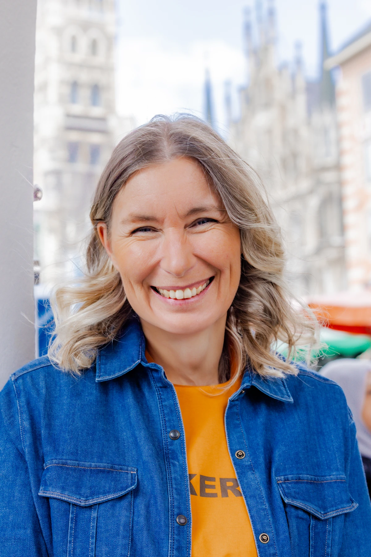 Lachende Unternehmerin in Jeansjacke und gelbem Oberteil im Personal Brand Portrait