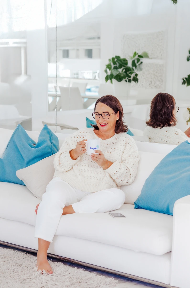 Frau mit Tasse auf Sofa Frau mit Brille und Tasse sitzt auf hellem Sofa. Fotografin: Manuela Engelking. Aufnahmeort: Palma auf Mallorca.
