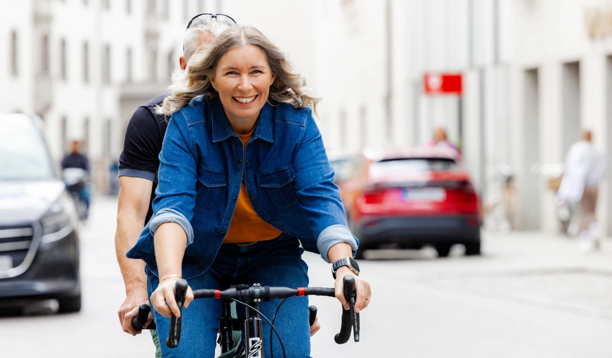 Unternehmerin fährt in Jeansjacke auf dem Fahrrad. Fotografin: Manuela Engelking. Aufnahmeort: München.