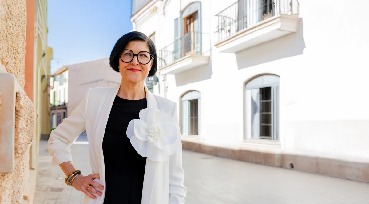 Unternehmerin mit Brille steht im weißen Blazer in Gasse. Fotografin: Manuela Engelking. Aufnahmeort: Mallorca.