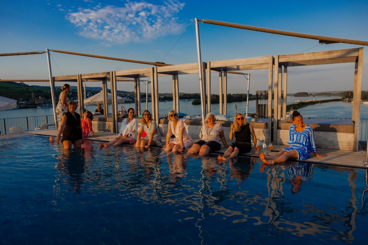 Frauen am Poolrand Frauen sitzen am Rand eines Pools mit Blick auf eine Flusslandschaft