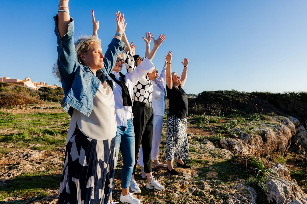 Frauengruppe unter blauem Himmel Gruppe von Frauen steht mit erhobenen Armen im Freien unter blauem Himmel