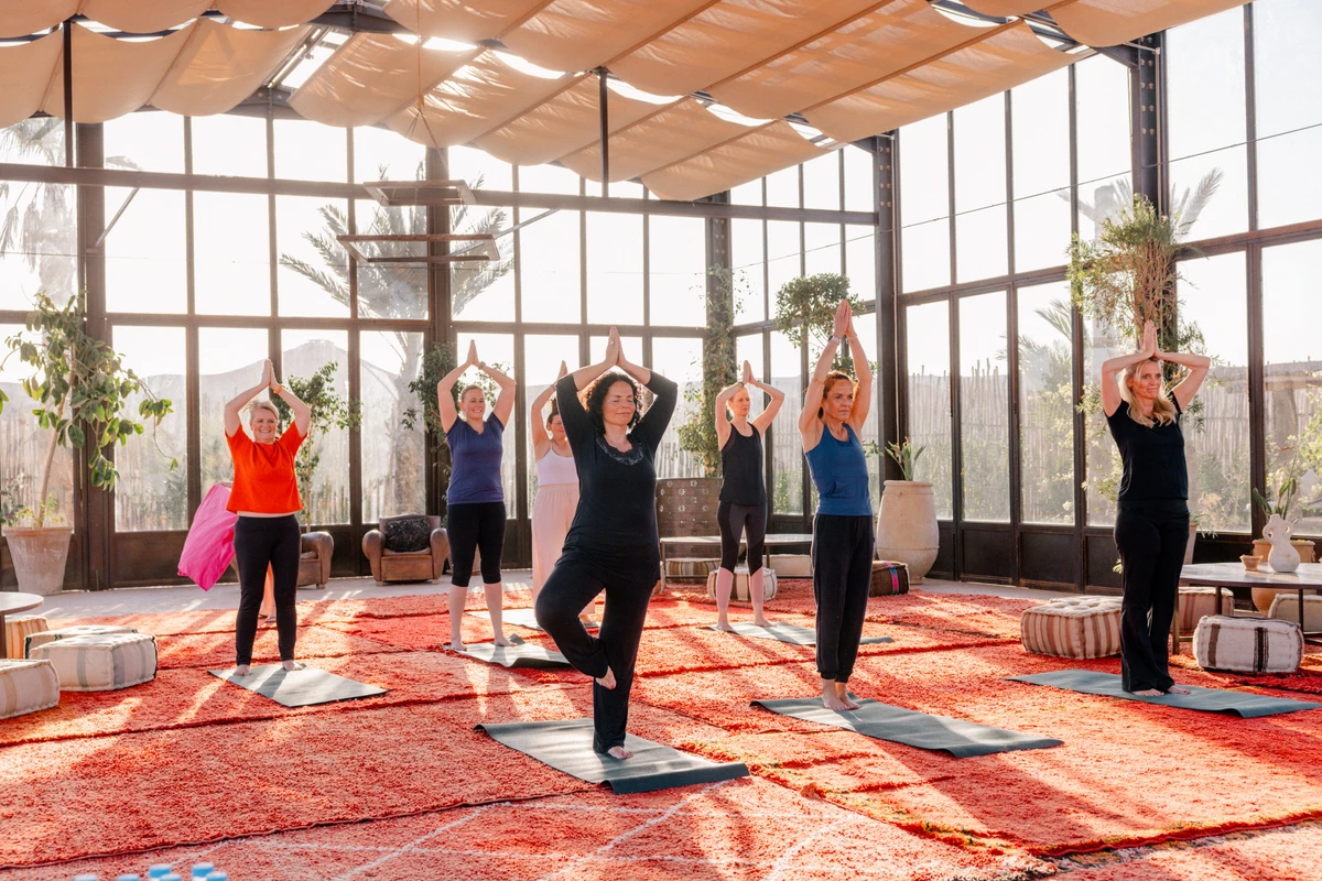 Yogaübung in der Gruppe Frauen machen gemeinsam Yoga in einem hellen Raum mit orangefarbenem Teppich